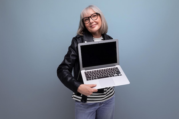 Inteligentna, nowoczesna, dojrzała starsza pani biznesowa o siwych włosach demonstruje posiadanie laptopa z makietą