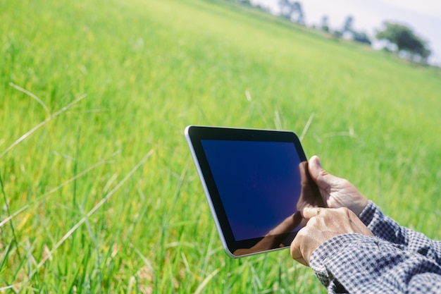 Inteligentny farmer używa tabletu do monitorowania i analizowania upraw w swoim gospodarstwie w słoneczny dzień.