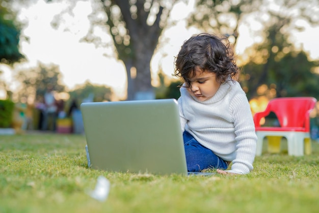 Inteligentny mały chłopiec bawi się w ogrodzie podczas korzystania z laptopa na koncepcji ubezpieczenia meadowhome