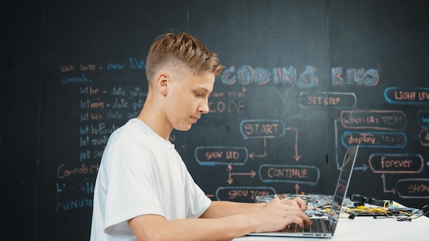 Inteligentny nastolatek kodujący lub programujący system przy stole z sprzętem Edification