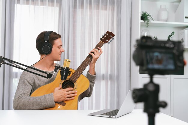 Inteligentny piosenkarz nagrywający przez kamerę grający na gitarze wraz z śpiewem pieniężny