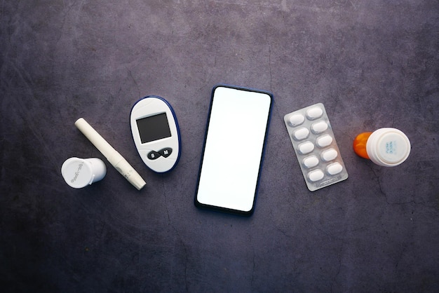 inteligentny telefon i narzędzia do pomiaru cukrzycy oraz pigułki na stole