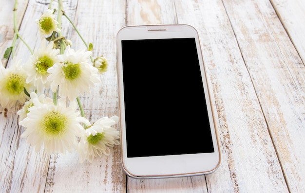 Zdjęcie inteligentny telefon i świeże kwiaty na białym stole z drewna