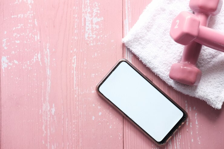 Inteligentny telefon ze sprzętem sportowym na różowej przestrzeni.