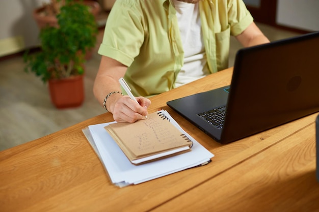 Internet do nauki i poszukiwania pracy Mężczyzna robi notatki w notatniku