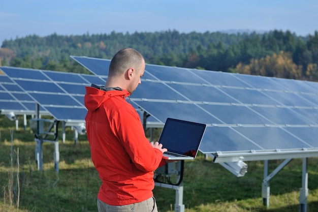 inżynier biznesu korzystający z laptopa przy panelach słonecznych roślina eko pole energii w tle