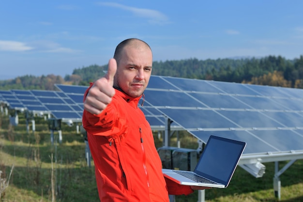 inżynier biznesu korzystający z laptopa przy panelach słonecznych roślina eko pole energii w tle