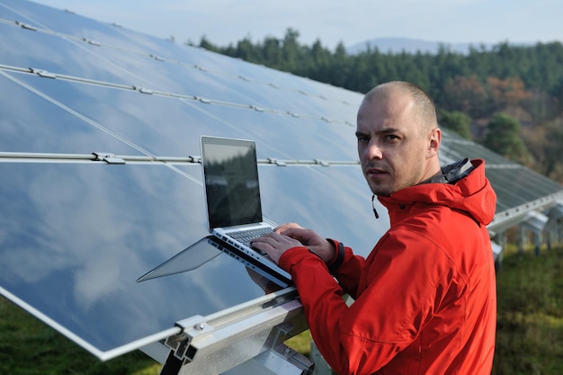 inżynier biznesu korzystający z laptopa przy panelach słonecznych roślina eko pole energii w tle