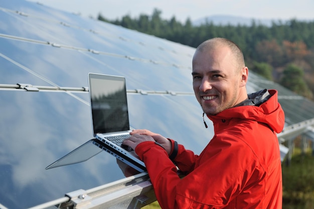 inżynier biznesu korzystający z laptopa przy panelach słonecznych roślina eko pole energii w tle