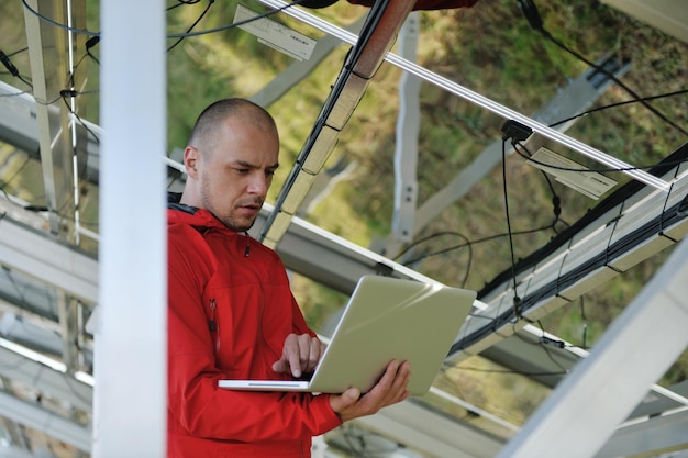 inżynier biznesu korzystający z laptopa przy panelach słonecznych roślina eko pole energii w tle