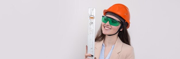 Inżynier Dziewczyna W Pomarańczowym Kasku Budowlanym Z Poziomem Budynku W Dłoniach Na Białym Tle