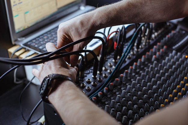 Inżynier dźwięku podłączając kabel audio jack do miksera studyjnego.