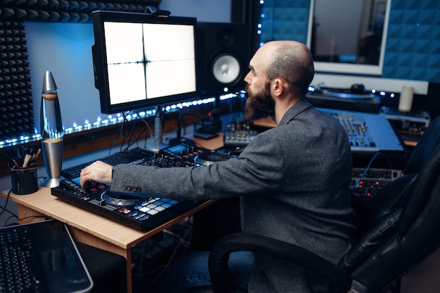 Inżynier dźwięku spoglądający na monitor na zdalnym panelu sterowania w studiu nagrań.