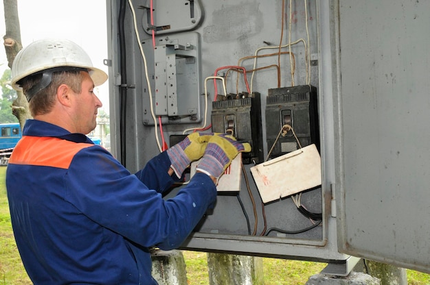 Inżynier elektryk wyłącza napięcie na linii zasilającej w elektrycznej szafie sterowniczej.