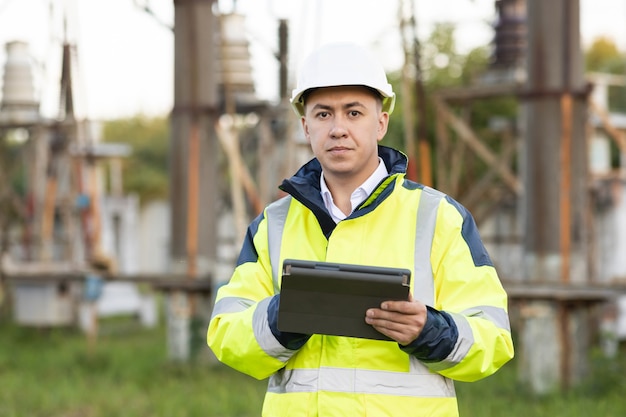 Inżynier elektryk z słupem wysokiego napięcia, inżynier energetyki w specjalnych ubraniach