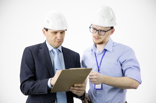 Inżynier i architekt w twardych kapeluszach omawiają projekt, robiąc notatki w schowku
