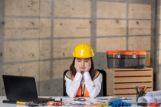 Zdjęcie inżynier pracownik cywilny w kasku i kamizelce inteligentna młoda urocza brunetka zmęczona