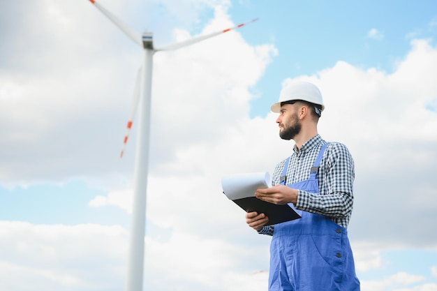 Inżynier sprawdza produkcję energii na turbinie wiatrowej Pracownik w parku wiatraków