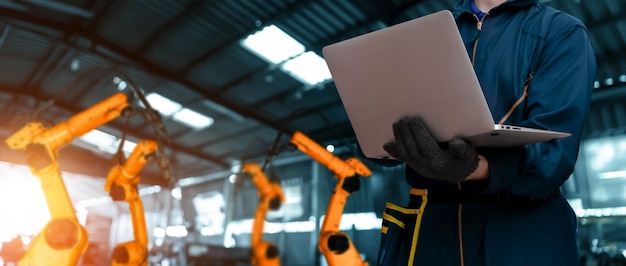 Zdjęcie inżynier używa zaawansowanego oprogramowania zrobotyzowanego do sterowania ramieniem robota przemysłowego w fabryce