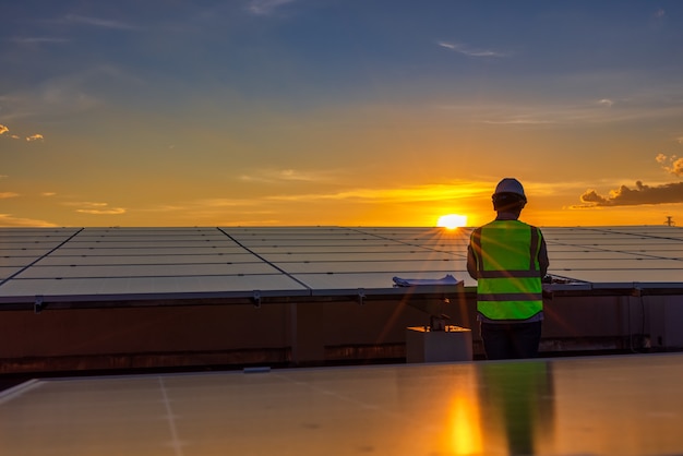 Inżynier za pomocą laptopa na panele słoneczne na dachu o zachodzie słońca niebo, inżynier pracujący w farmie fotowoltaicznej. Ekologiczna technologia dla energii elektrycznej