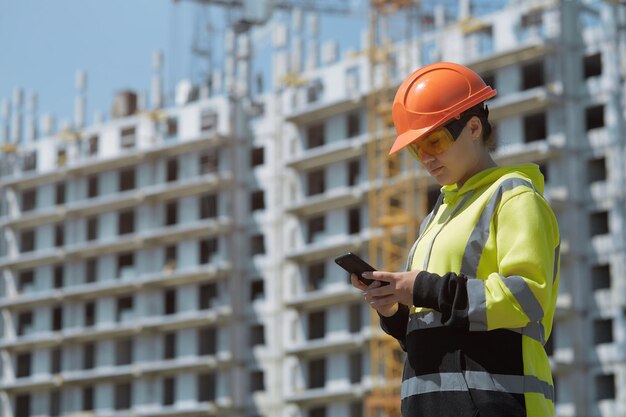 Inżynierka w kasku pracuje przez telefon na tle budowy