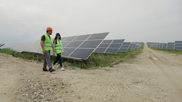 Inżynierowie mężczyzna i kobieta kontrolujący panele słoneczne w specjalnym mundurze spaceru omawiają instalację słonecznych baterii inżynier środowiska. Produkcja czystej energii.
