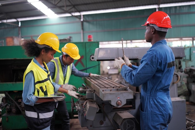 Inżynierowie przemysłowi płci męskiej i żeńskiej rozmawiają z pracownikiem fabryki na tle maszyn i urządzeń. Pracują w Wytwórni Przemysłu Ciężkiego.