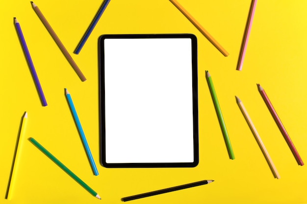 iPad pro z białym ekranem na żółtym tle z płasko ułożonym rysikiem Apple Pencil