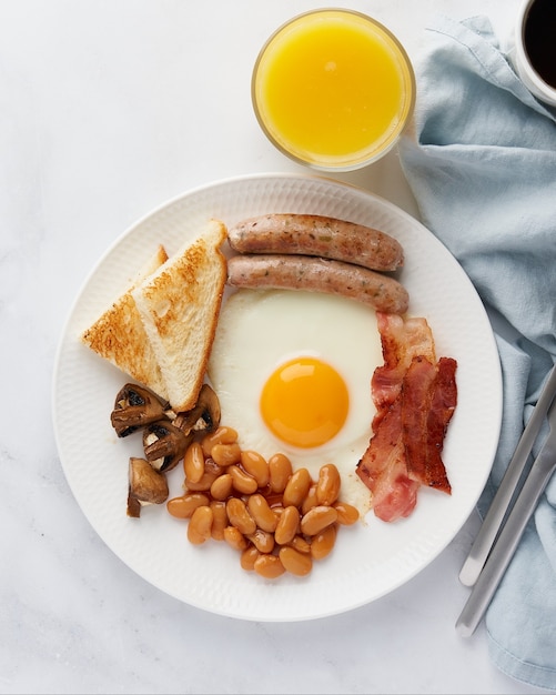Irlandzkie klasyczne śniadanie jajka sadzone grillowane kiełbaski grzyby boczek fasola kawa sok pomarańczowy
