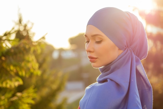 Islamska piękna kobieta w muzułmańskiej dziewiczej sukience stojąca na letnim parku na tle ulicy las jesienne drzewa