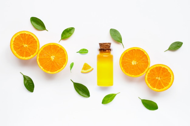 Zdjęcie istotny olej z świeżą pomarańczową cytrus owoc z liśćmi odizolowywającymi na bielu