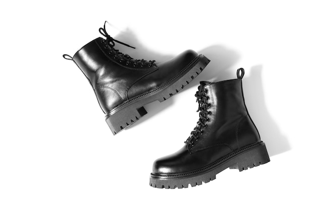 Izolowane skórzane czarne buty z jednym wchodzeniem na drugie z cieniami padającymi na białe tło Buty w kolorze czarnym z obcasem blokowym, okrągłym czubkiem i wytłoczoną twardą podeszwą