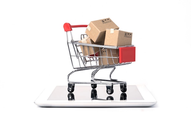 Izolowane wysyłanie pudełek papierowych wewnątrz Czerwony wózek na zakupy na tablecie z białym tłem i kopia przestrzeń, zakupy online i koncepcja e-commerce.