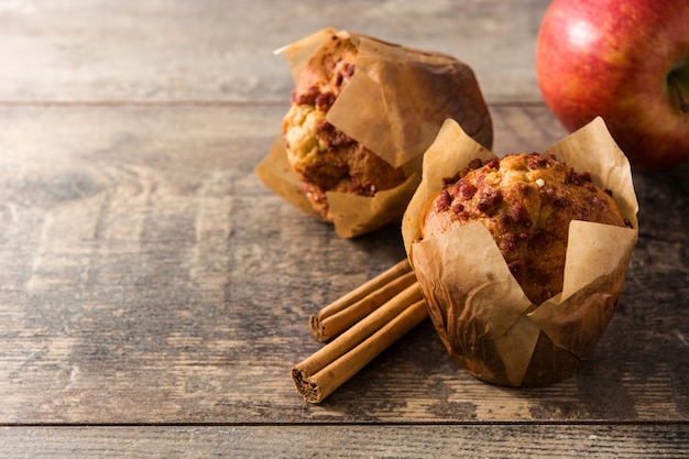 Jabłka i cynamonowi muffins na białym drewnianym stole. Skopiuj miejsce