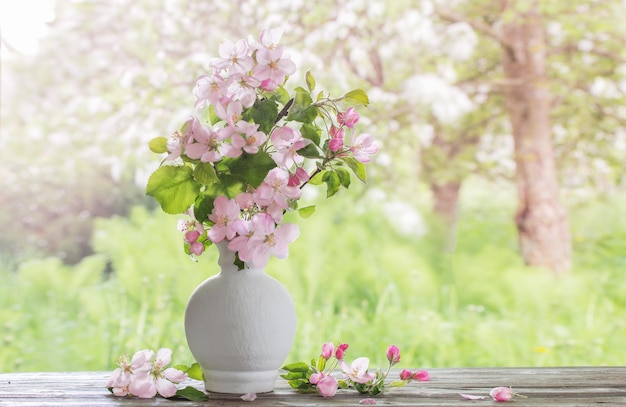 Jabłko kwiaty w białym wazonie na tle wiosennego ogrodu