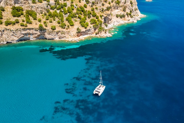Jacht katamaran w pobliżu skalistego wybrzeża w Turcji Luksusowe wakacje na morzu