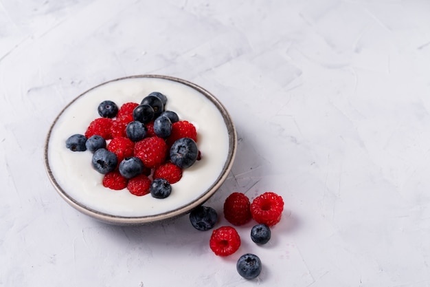jagody jogurt w ceramicznej misce na białym stole