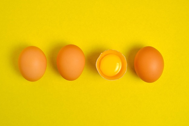 Jaja kurze na żółtym tle przełamane żółtkiem.