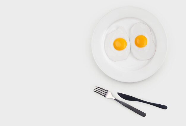 jajka sadzone z dwóch jajek na białym talerzu na białym tle