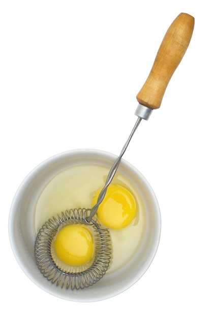 Jajka surowe na talerzu i mikserze z drewnianą rączką