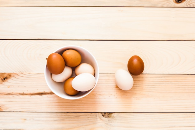 Jajka w ceramicznej misce, talerz na drewnianym tle, przygotowanie do Wielkanocy, produkty rolne, kurczak i jajko, dekorowanie domu na wakacje