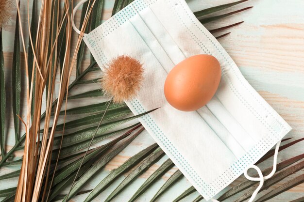 Jajko kurczaka w masce medycznej na twarz i gałąź palmowa Święto Wielkanocne podczas pandemii koronawirusa