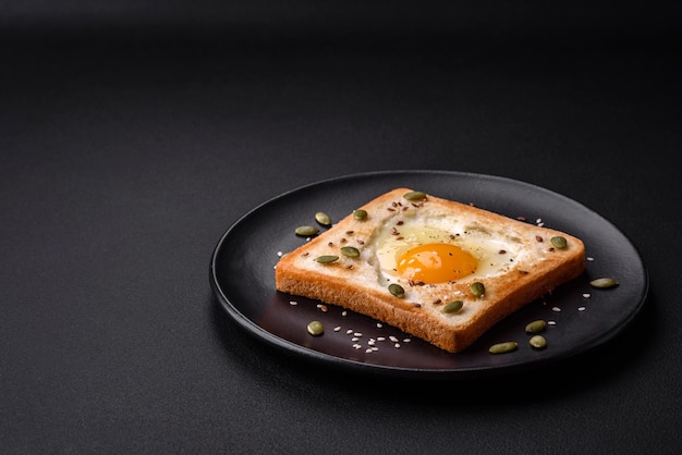Jajko sadzone w kształcie serca w toście chlebowym z sezamem, siemieniem lnianym i pestkami dyni na czarnym talerzu