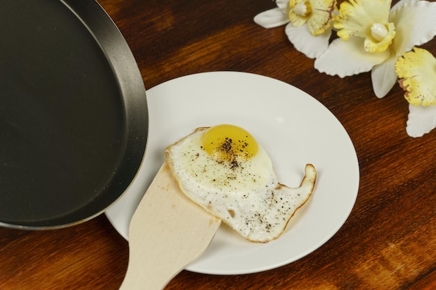Jajko sadzone wyjmuje się szpatułką z patelni na białym talerzu