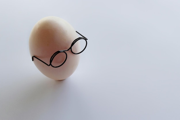 Jajko w białej skorupce nosi okulary na białym tle z miejscem na tekst