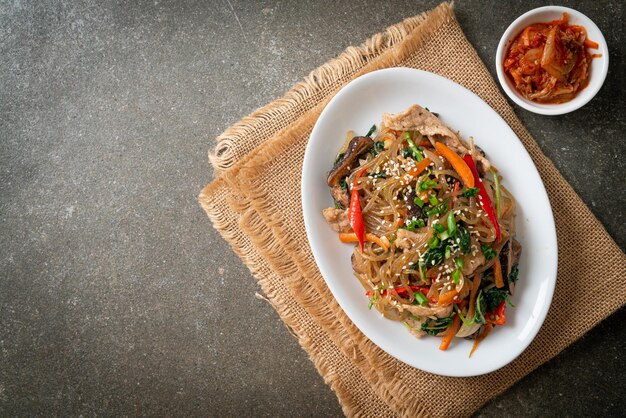 Japchae lub smażony koreański makaron vermicelli z warzywami i wieprzowiną polany białym sezamem