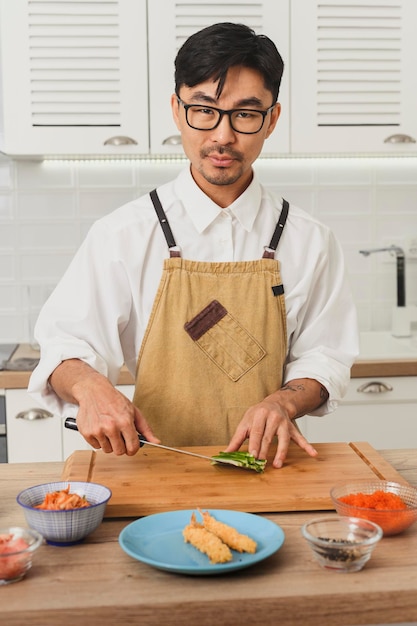 Japonia koncepcja dostawy żywności widok z przodu portret azjatyckiego uśmiechniętego szefa kuchni w mundurze krojenia ogórków