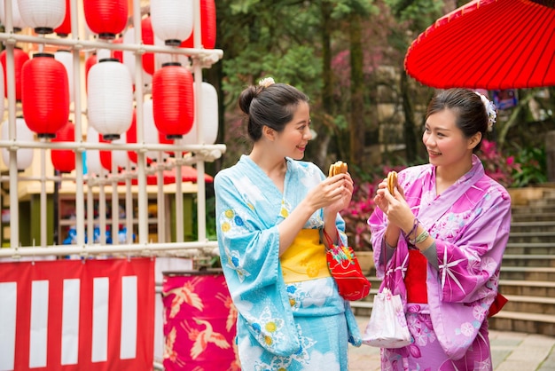 Japonki udające się do miejscowej kapliczki, próbujące pysznych przekąsek dorayaki, dzielące się razem, cieszą się świąteczną dekoracją latarni ubrane w tradycyjne kimono.