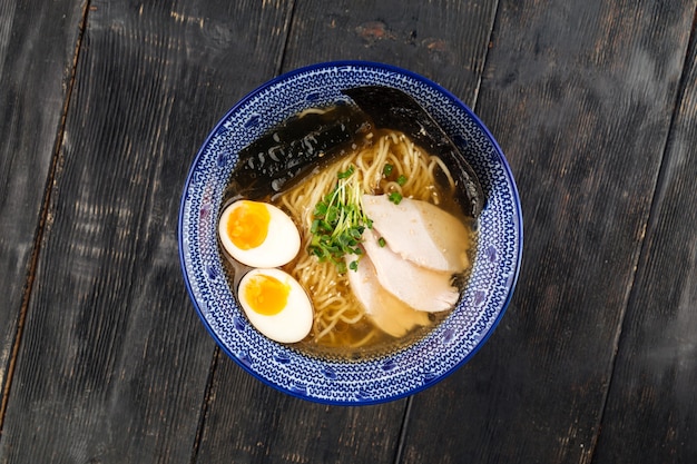 Zdjęcie japońska zupa z makaronem shio ramen z piersią kurczaka na drewnianym stole