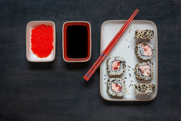 Japoński mus z mięsem kraba sushi z czerwonym kawiorem na marmurowej kamiennej płycie z pałeczkami